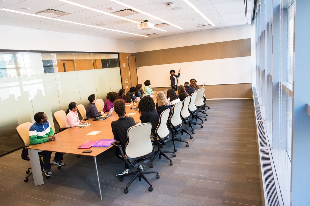 Offerings A diverse group actively collaborating in a bright, modern conference room setting.