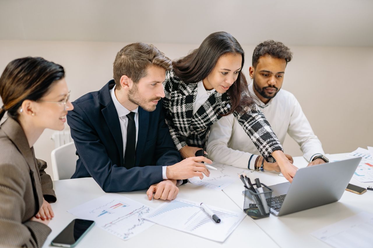 Mastering the First Impression: Your intriguing post title goes here Diverse team of professionals working together on a laptop, analyzing charts and data in an office setting.